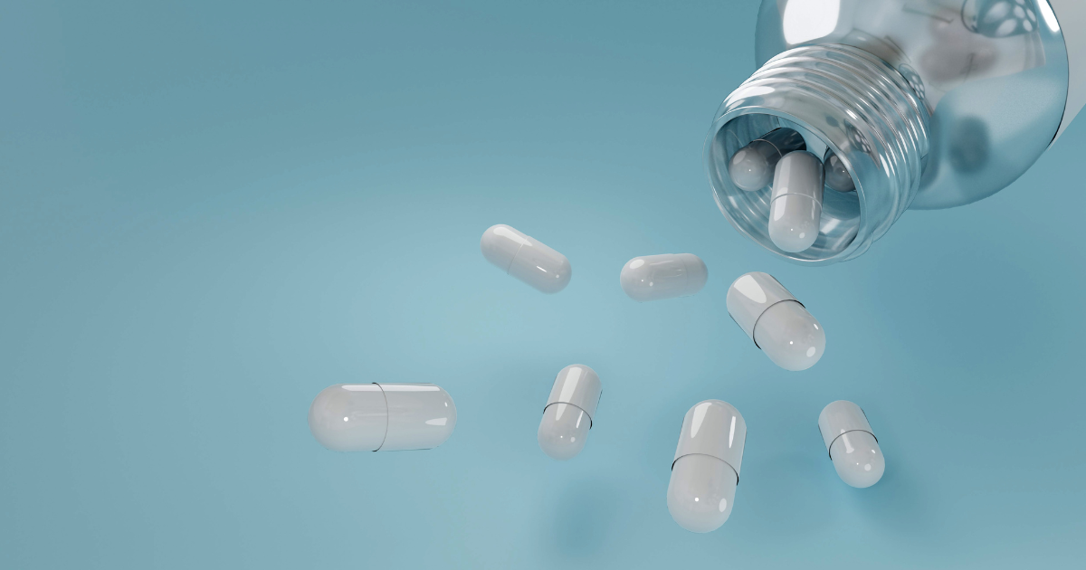 White capsules spilling from a prescription bottle representing modafinil vs Adderall comparison